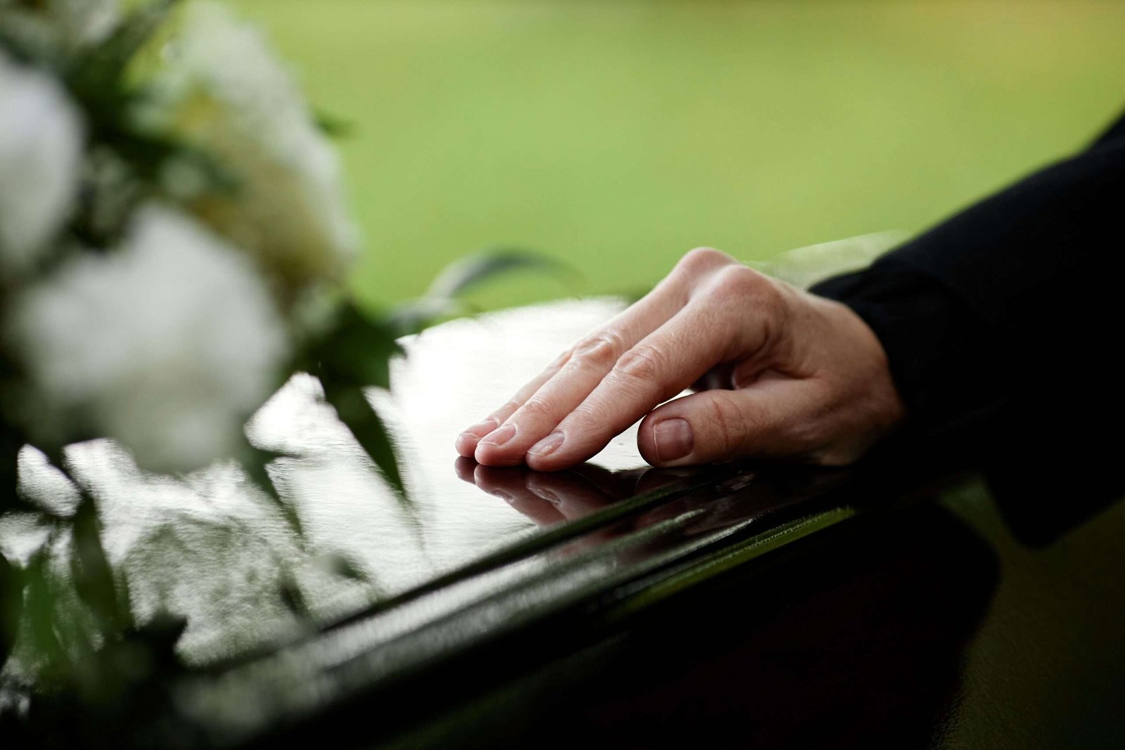 Closeup of womans hand on coffin Closeup of womans hand on coffin saying goodbye at outdoor funeral ceremony, copy space